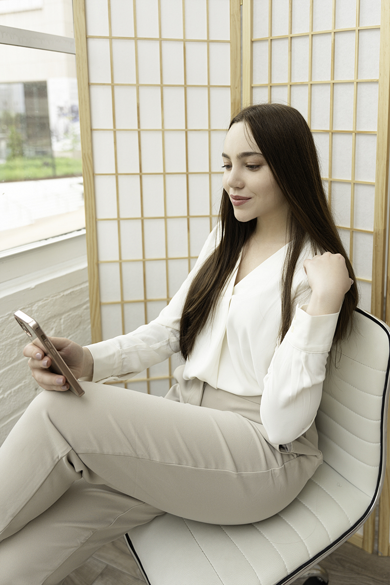 A woman sits in a modern office chair under a window during her Baltimore Personal Brand Photos