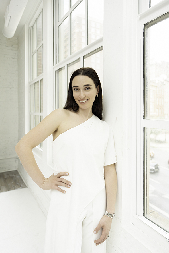 A woman in a white outfit leans against a wall in windows after learning to Invest in Personal Branding Photos